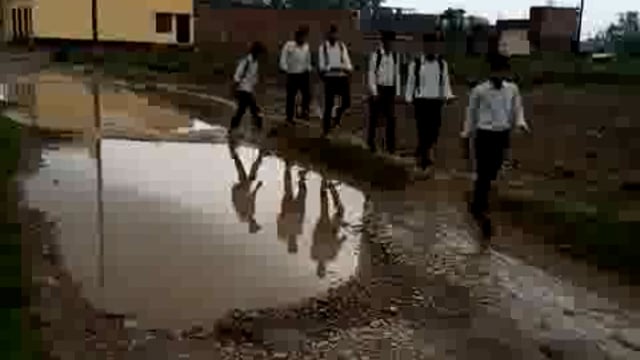 जलभराव के मध्य से गुजरते विद्यार्थी 