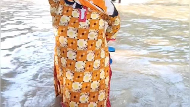 वृंदावन में यमुना में आई बाढ़ के पानी से हुए जल-भराव के बीच से होकर गुजरती वृद्ध महिला।